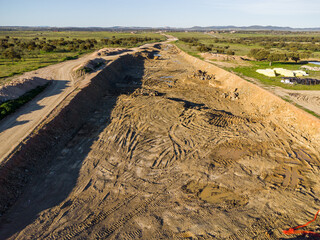 Aerial View of Highway Construction: Raw Earth Trench Cutting Through Landscape to Horizon.