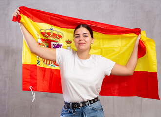 Portrait of young female supporter of the Spanish team wearing the national flag