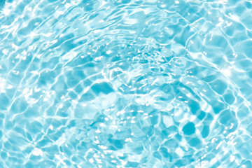 Blue water with ripples on the surface. Defocus blurred transparent blue colored clear calm water surface texture with splashes and bubbles. Water waves with shining pattern texture background.