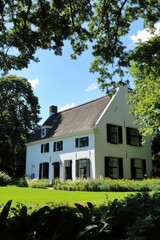 Beautiful white house in a garden surrounded by trees on a sunny day with blue skies, capturing the essence of serene country living and nature's tranquility