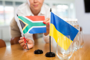 Closeup of national flags of Ukraine and South Africa in hands of female office secretary preparing...