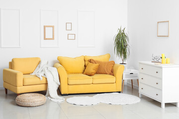 Interior of stylish living room with cozy yellow sofa, armchair and chest of drawers