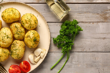 Plate of boiled baby potatoes with dill and tomatoes on grey wooden background