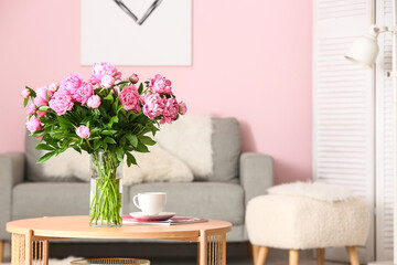 Vase of pink peonies on coffee table with couch in living room