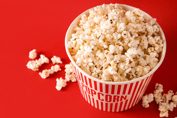 Bucket with tasty popcorn on red background