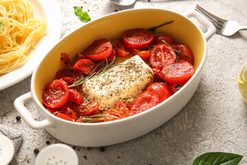 Baking dish with tomatoes and feta cheese on grey background