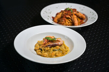 spaghettoni di pasta fresca con gamberi e pomodori rossi, serviti in un piatto bianco al ristorante