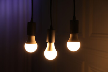 Glowing light bulbs hanging near wall, closeup