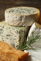 Different types of cheese and rosemary on blurred background, closeup