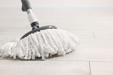 String mop on wooden floor indoors, space for text. Cleaning equipment