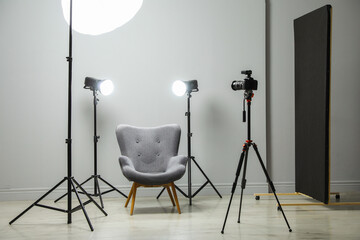 Professional lighting equipment and armchair in photo studio