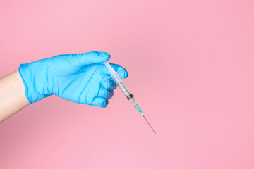 Doctor holding syringe with medication on pale pink background, closeup. Space for text