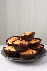 Delicious muffin with chocolate chips on light grey table