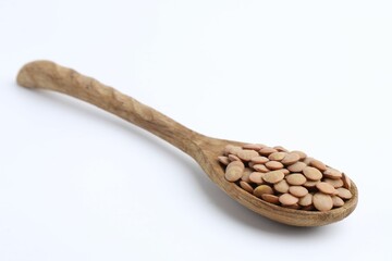 Raw lentils in wooden spoon isolated on white