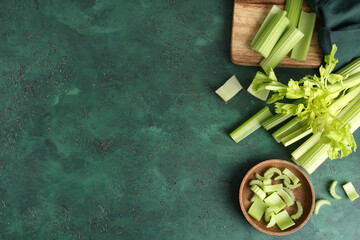 Wooden board and bowl with fresh green celery on color background