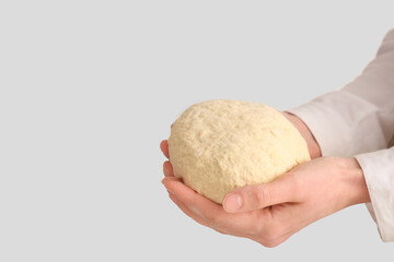Woman holding fresh raw dough on white background
