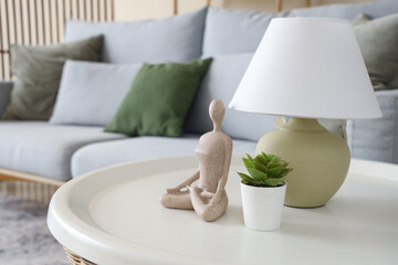 Lamp with plant and statuette on table in living room, closeup