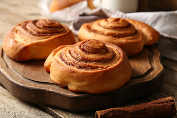 Board with sweet cinnamon rolls on wooden background
