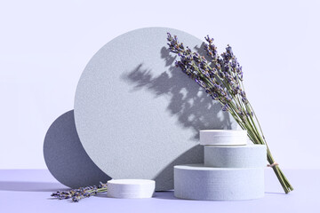 Decorative podiums with lavender flowers on lilac background