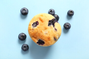 Tasty blueberry muffin on blue background, closeup