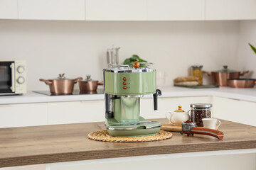 Modern green coffee machine with jar of beans on table in kitchen
