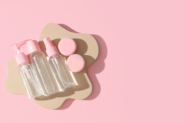 Plaster podium with travel cosmetic products on pink background