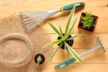 Gardening tools with shovel, rake and straw hat on beige wooden background. Top view