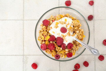 Bowl of tasty granola and yogurt on light tile background