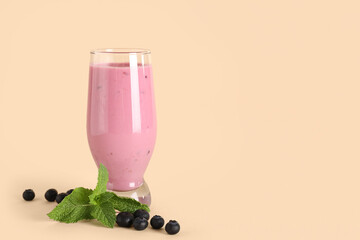 Glass of fresh blueberry smoothie with mint and berries on yellow background