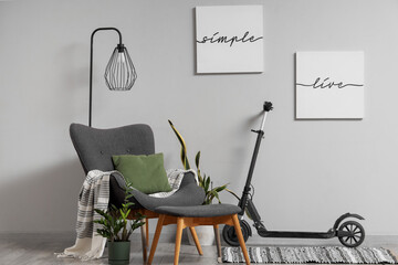 Interior of living room with electric scooter, armchair and lamp