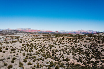 aerial view of desert landscape with red rock mountains in the background