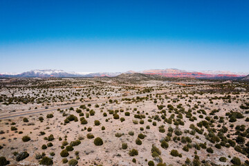 aerial view of desert landscape with snowy red rock mountains in the background