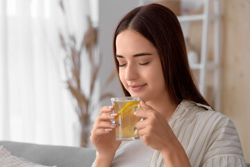 Young woman with cup of green tea at home on autumn day, closeup