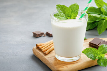 Mint chocolate milkshake with fresh mint leaves displayed in a glass on a table with a relaxed retro ambiance