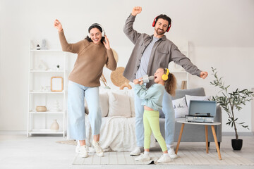 Happy parents with their little daughter in headphones and microphones singing karaoke at home