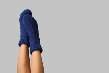 Legs of young woman in blue knitted socks on grey background