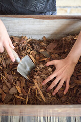 Close-up of composting process with hands and a trowel