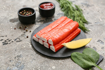 Black board with tasty crab sticks and different spices on grey background © Pixel-Shot