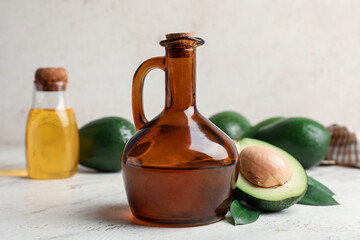 Jug of avocado oil on light background