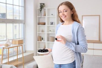 Young pregnant woman with dried prunes at home