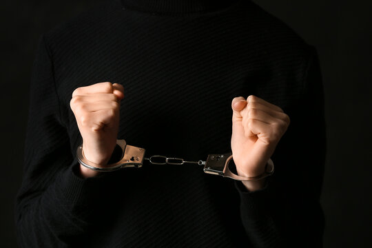 Young woman in handcuffs on black background, closeup