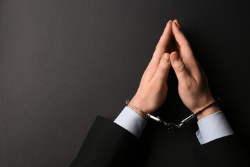 Businessman hands in handcuffs on black background