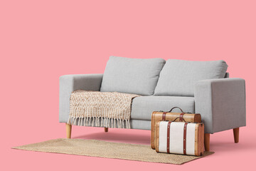 Stylish grey sofa with and vintage suitcases on pink background