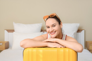 Female tourist with sunglasses and suitcase in hotel room