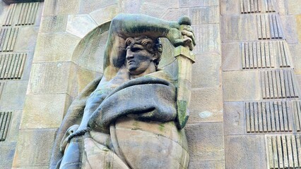 Stone statue of a muscular figure holding a sword above their head on the La Patria Vincitrice in...