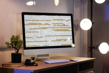 Computer monitor with programming code on desk in office at night