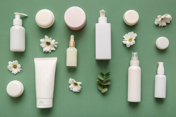 Different cosmetics and beautiful flowers on green background