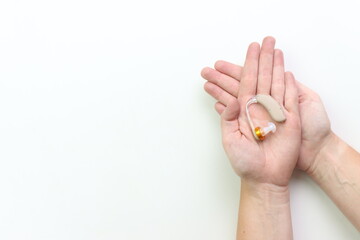 Woman holding a hearing impairment device in the hands with a white background and copy space in the left side 
