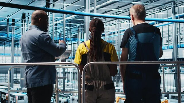 Manager supervising photovoltaic smart factory workers designing production lines in CAD software. Industry 4.0 solar panels plant team leader overseeing employees optimizing floor layouts, camera A
