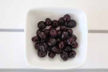 A Bowl of Blueberries on a white table . 